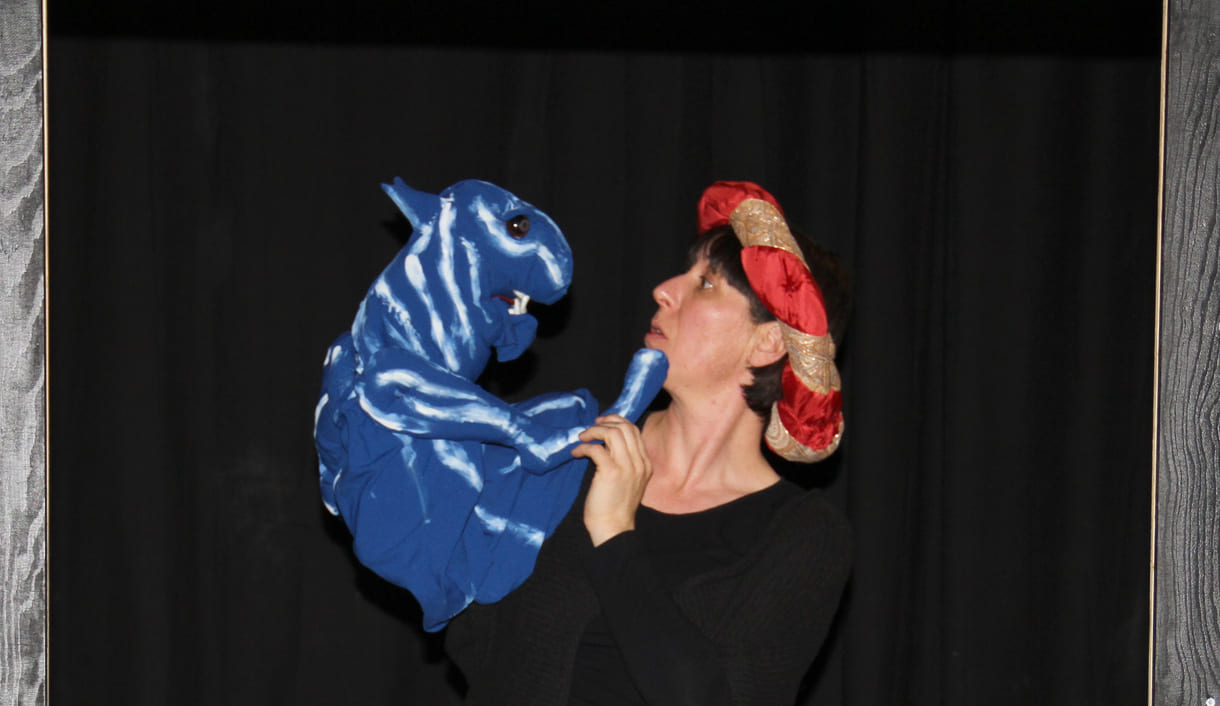 Die Puppenspielerin als Färber Hakim mit blauem Tiger als Handpuppe