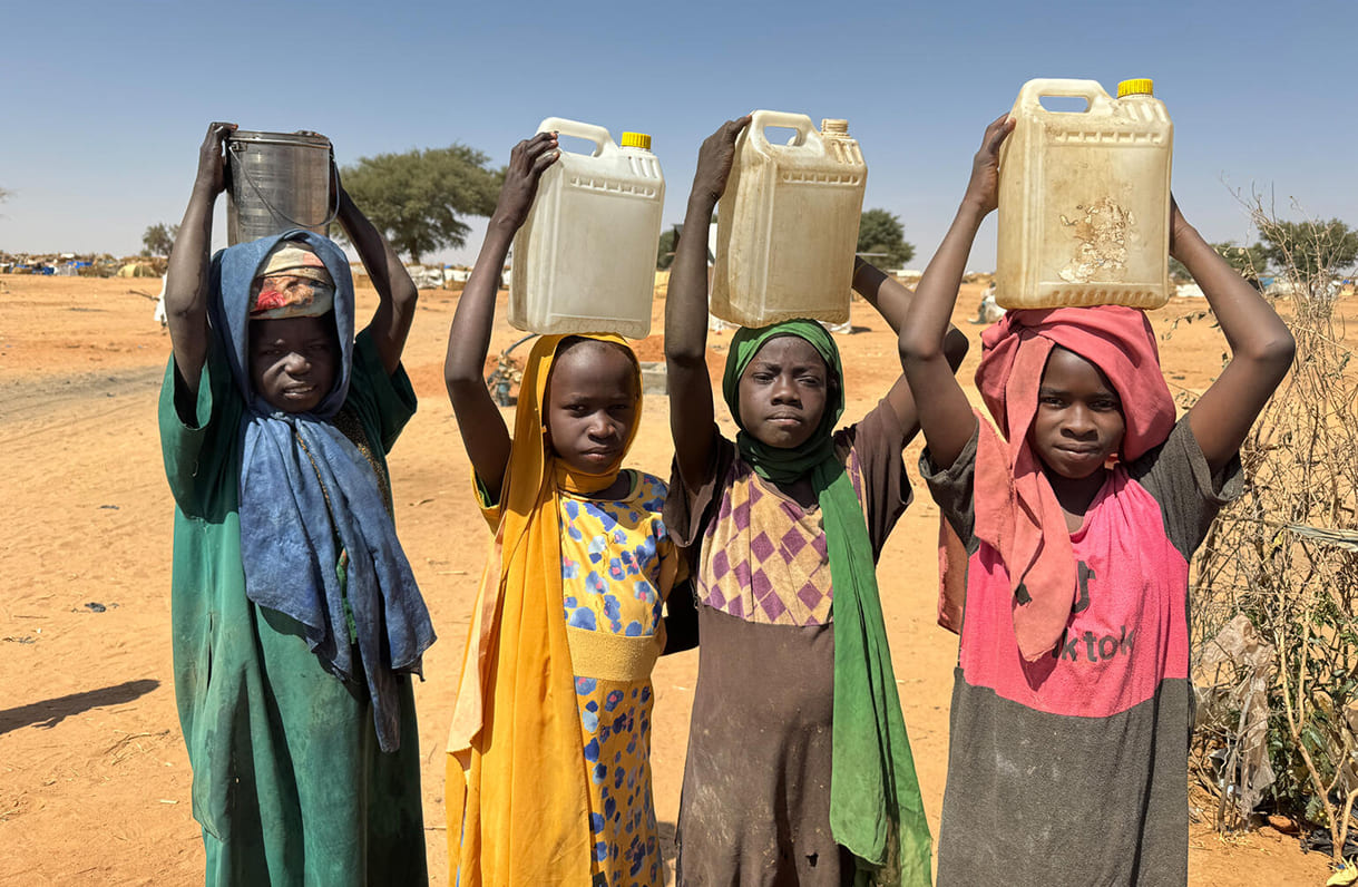 Am 3. Februar 2024 tragen Kinder Wasserbehälter, nachdem sie diese an einem UNICEF-Bohrloch in der Flüchtlingssiedlung Adré im Tschad gefüllt haben. Fast die Hälfte der im Tschad ankommenden sudanesischen Flüchtlinge überquerte die Grenze über Adré.