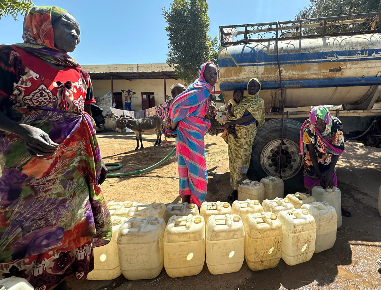 Am 6. Februar 2024 holen Frauen in Zelingei Town, Zentral-Darfur, Sudan, Wasser, das von einem Tankwagen über den UNICEF-Partner Jebel Marra Charity Organization for Rural Development (JMCO) zum provisorischen Lager für Vertriebene an der Al Rabad School geliefert wird.