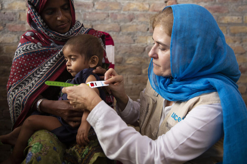 Am 3. November 2022 besucht Paloma Escudero, UNICEF-Direktorin für globale Kommunikation und Interessenvertretung, in Jacobabad, Provinz Sindh, Pakistan, ein Gesundheitszentrum in einem von Überschwemmungen betroffenen Gebiet in Pakistan. Sie führt eine Messung des mittleren Oberarmumfangs (MUAC) bei dem 2-jährigen Ali Hassan durch, der stark unterernährt ist.