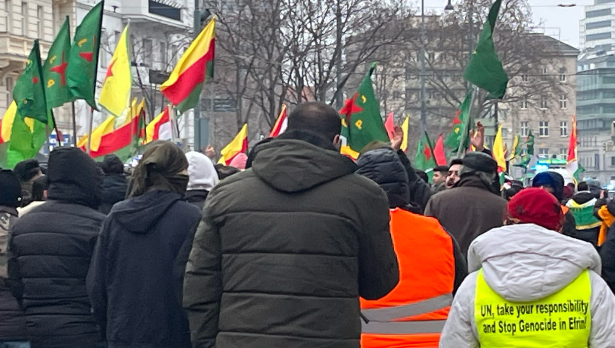 Auf der gelben Warnweste wird die UNO aufgefordert, den Völkermord in Efrin / Afrin zu stoppen