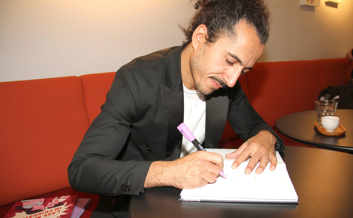 Autor Omar Khir Alanam signiert das Buch mit einer Widmung für KiJuKU
