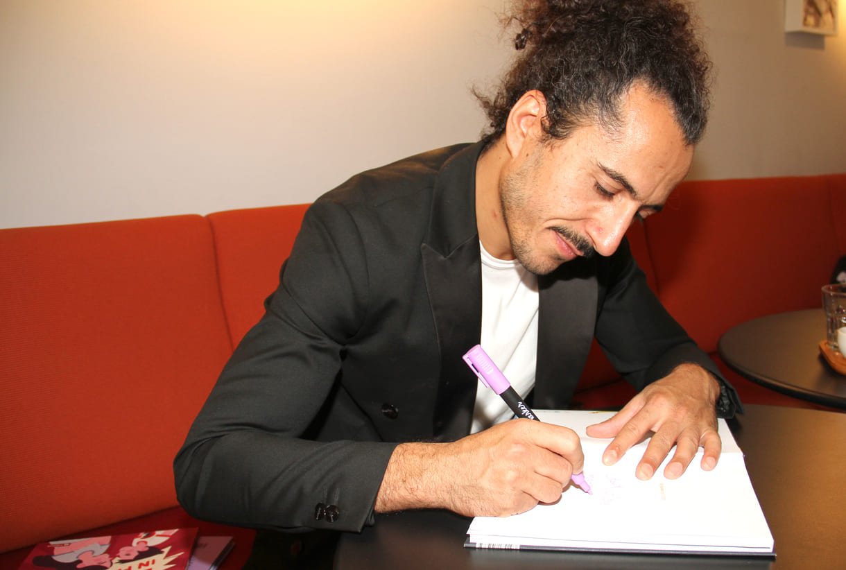 Autor Omar Khir Alanam signiert das Buch mit einer Widmung für KiJuKU