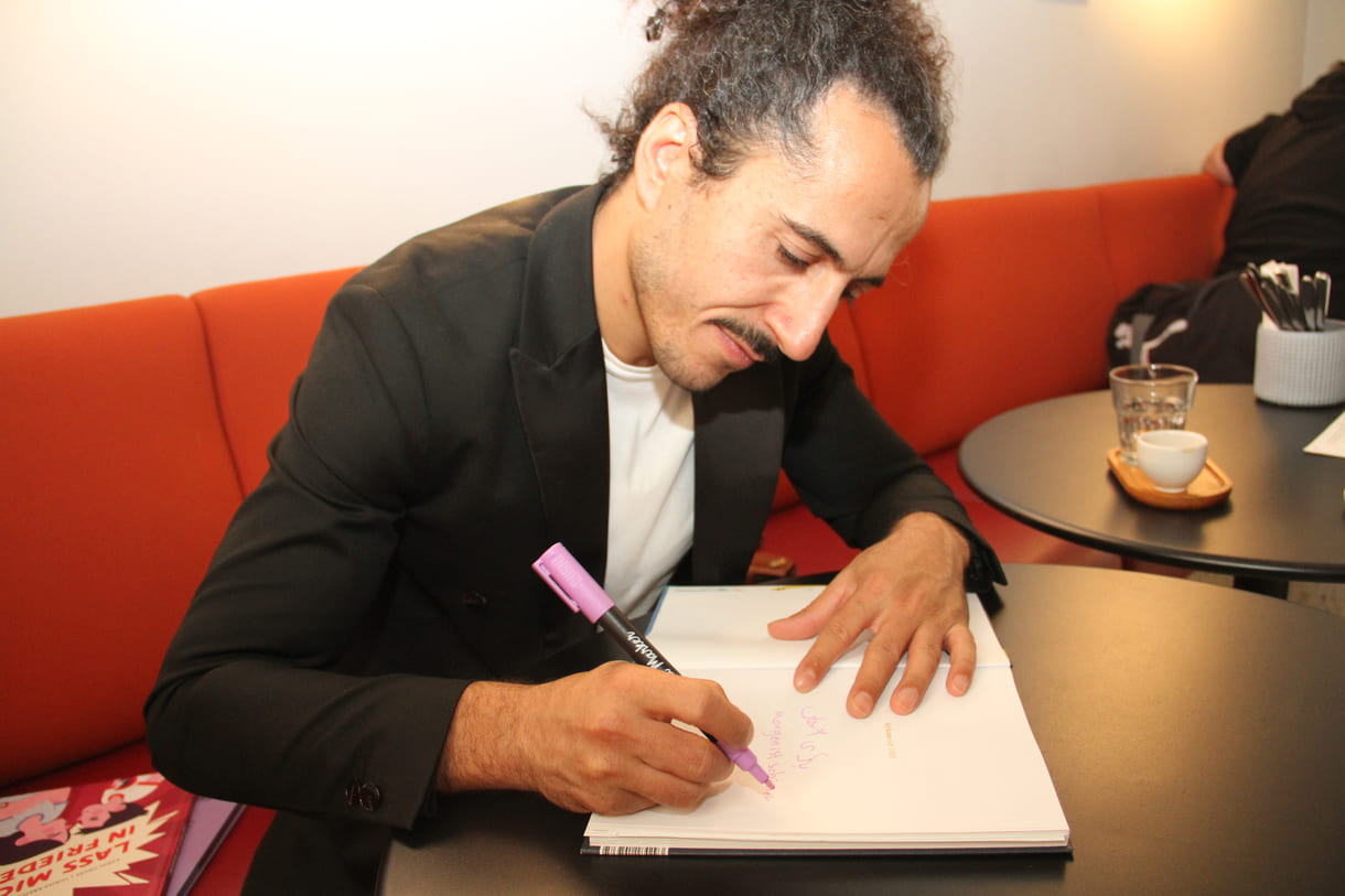 Autor Omar Khir Alanam signiert das Buch mit einer Widmung für KiJuKU