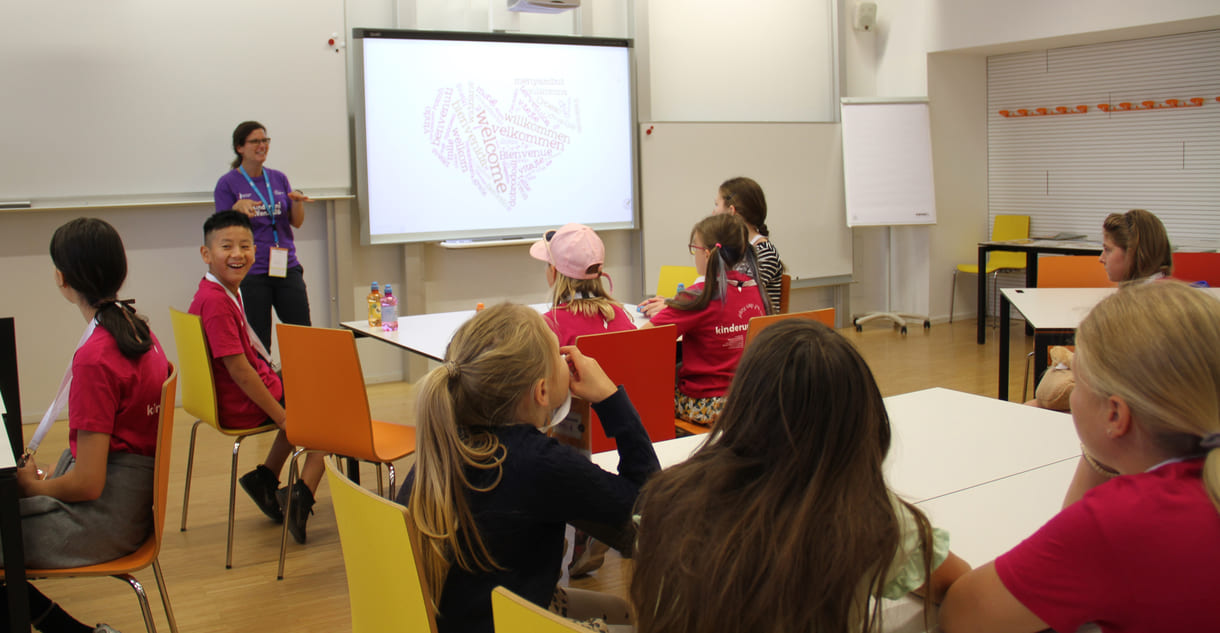 Kinderuni-Student:innen machen sich auf, durch den Raum zu gehen und einander zu begrüßen