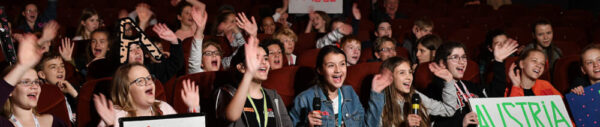 Hier sitzen Kinder im Kino und stimmen ab
