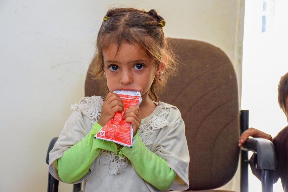 Ebtihal Muhammad, 7 Monate, mit seiner Mutter beim Essen einer energiereiche Paste aus Erdnussbutter in der Al Aman Health Unit – Gouvernement Hajjah im Jemen.