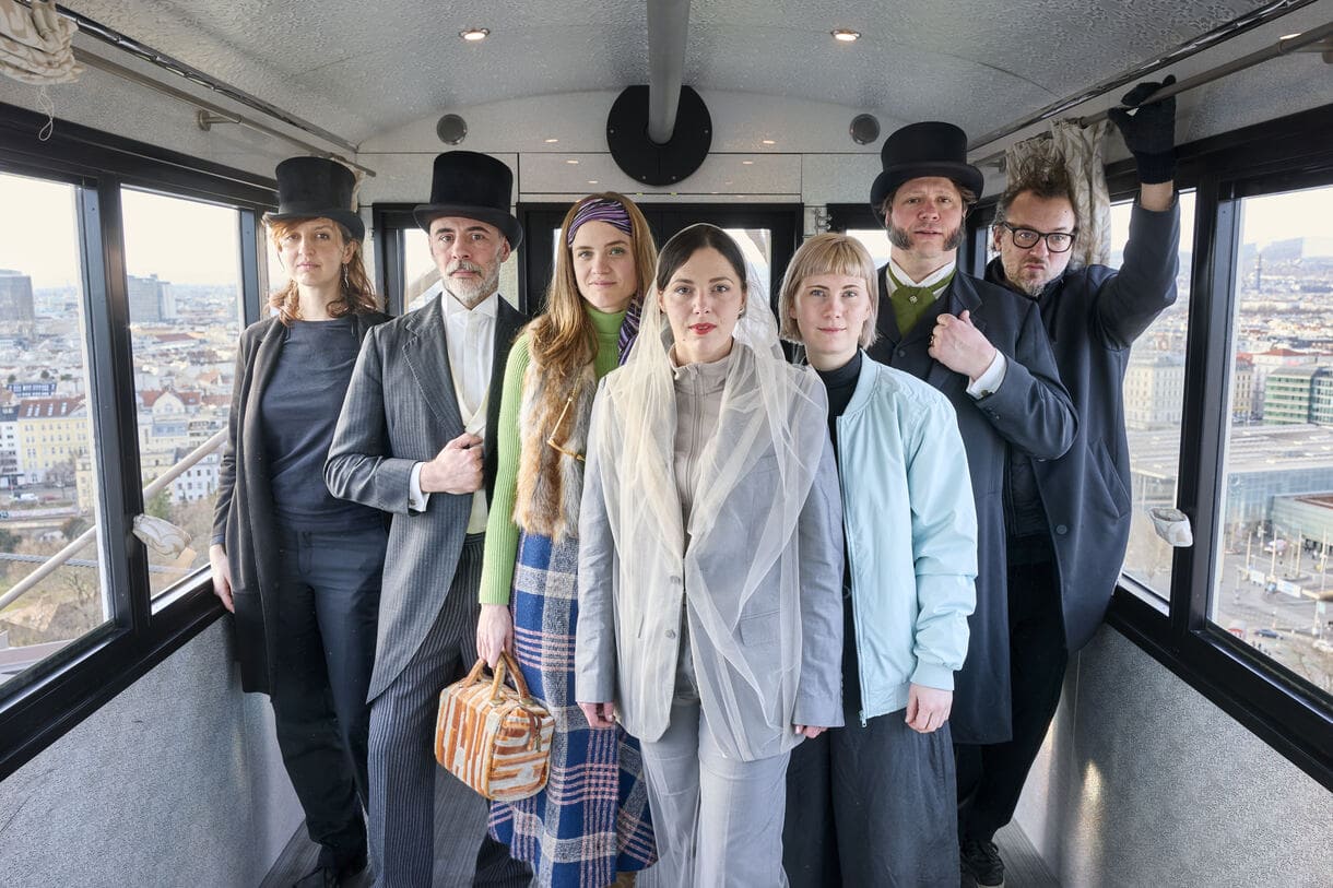 Teamfoto der Performer:innen in einem der Riesenrad-Waggons