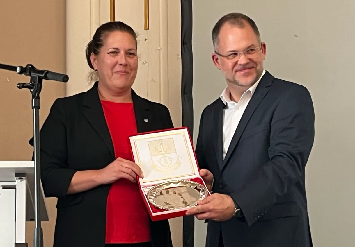 Bezirksvorsteherin Christine Dubravac-Widholm übergibt einen Brigittenauer Zinnteller an Schuldirektor Árpád Krämer