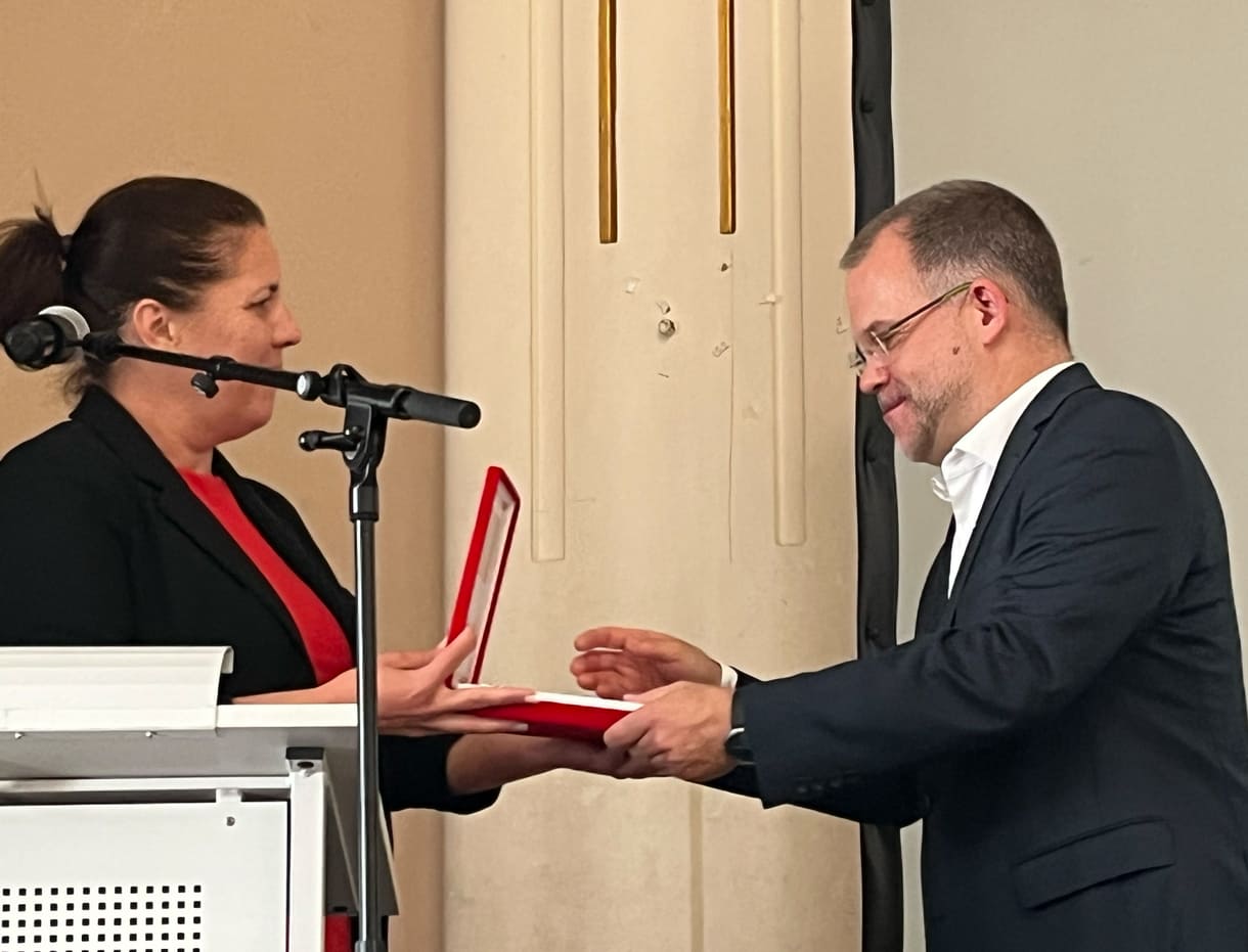 Bezirksvorsteherin Christine Dubravac-Widholm übergibt einen Brigittenauer Zinnteller an Schuldirektor Árpád Krämer