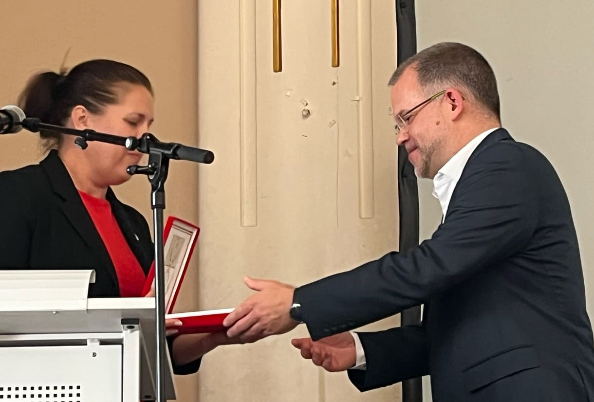 Bezirksvorsteherin Christine Dubravac-Widholm übergibt einen Brigittenauer Zinnteller an Schuldirektor Árpád Krämer